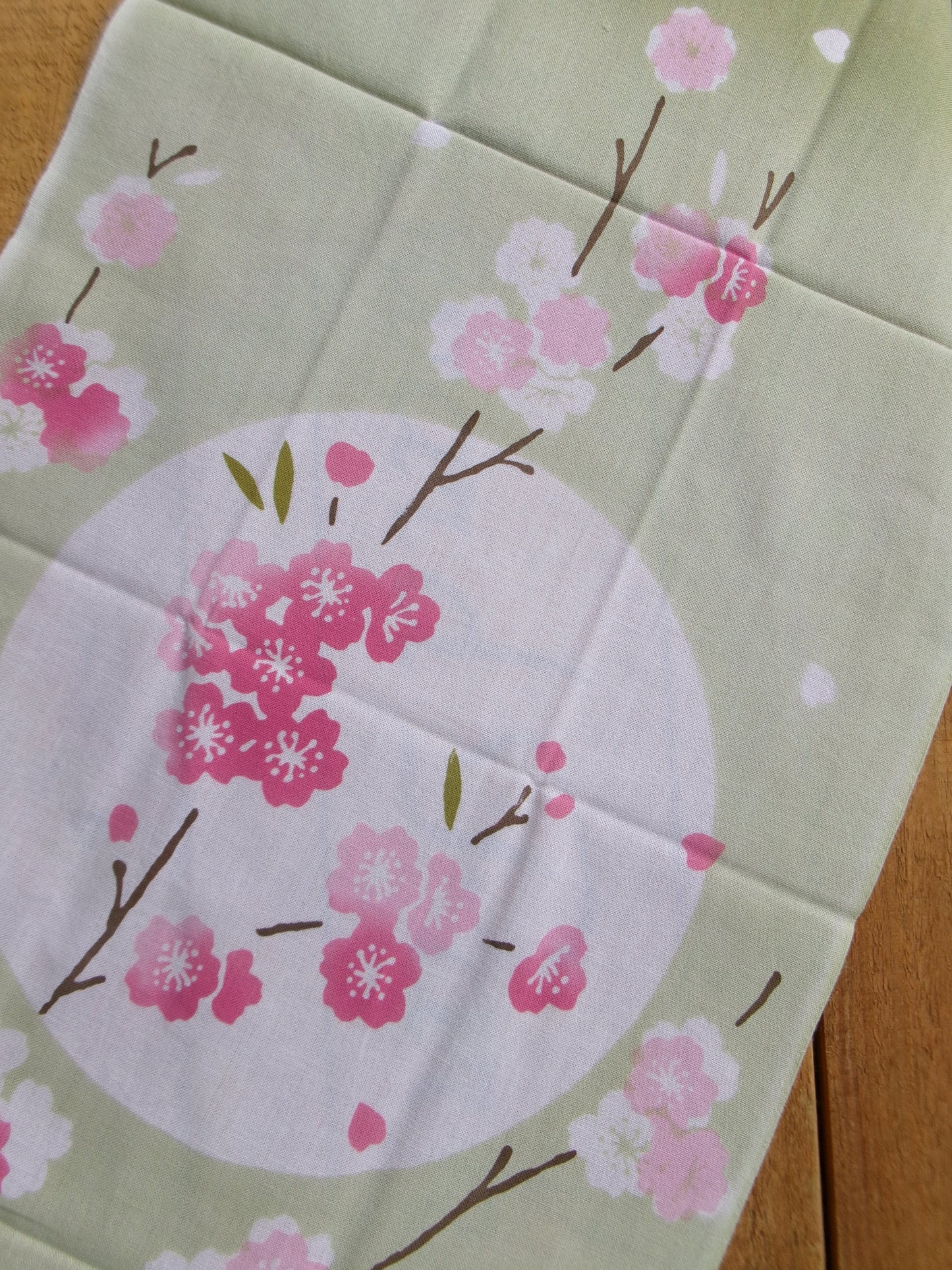 Japanese tenugui towel with cherry blossom design by Kamawanu, featuring delicate cherry blossoms and traditional fabric pattern.