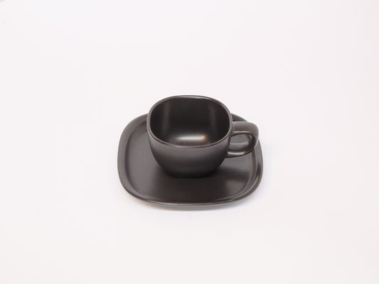Black and white coffee cup with matching saucer by 柳宗理, sleek ceramic design, minimalist style for elegant coffee moments.