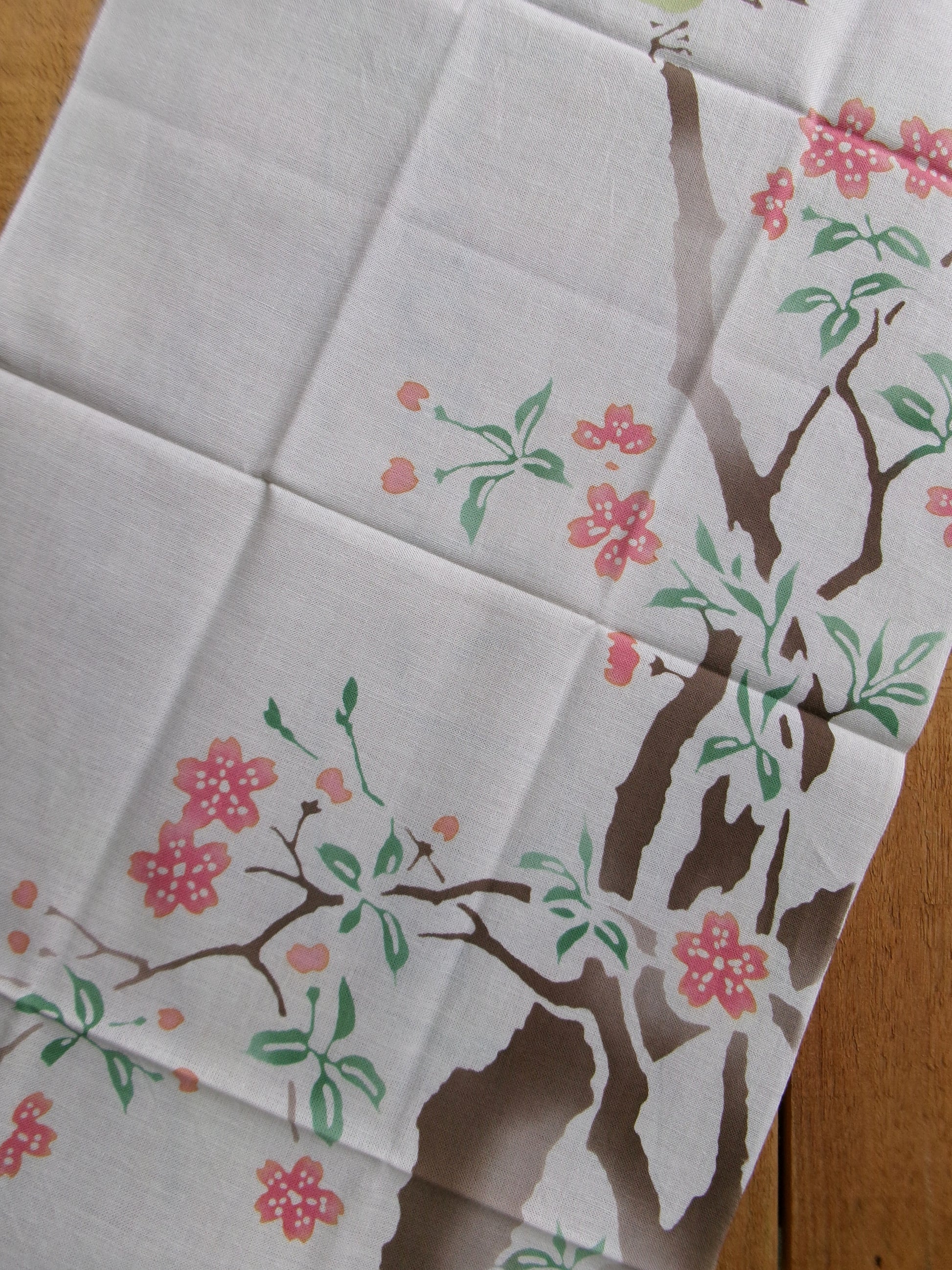 Japanese tenugui towel featuring cherry blossoms and a white-eye bird by Kamawanu, showcasing traditional floral design.