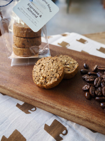 Three CIBI TOKYO STORE espresso and almond cookies on a plate, close-up view of crispy, golden-brown baked cookies.