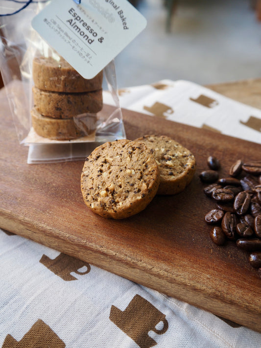 Three CIBI TOKYO STORE espresso and almond cookies on a plate, close-up view of crispy, golden-brown baked cookies.