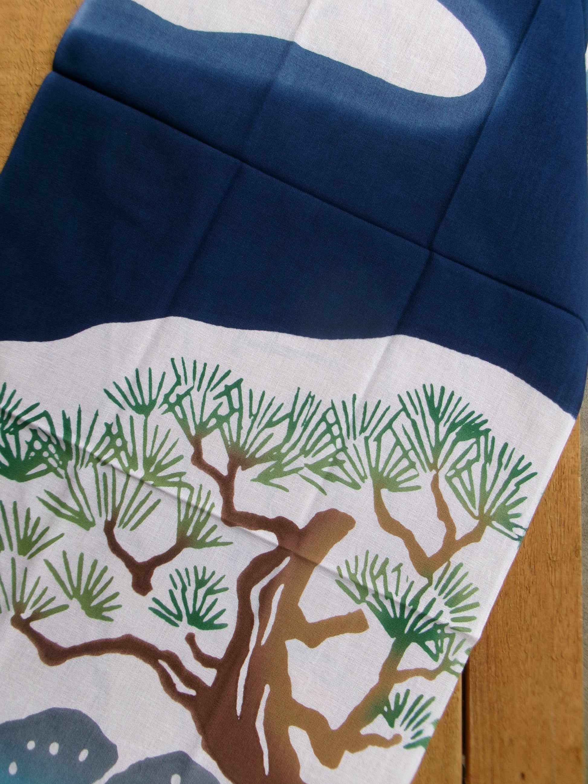 Traditional Japanese tenugui towel featuring Mount Fuji and hot springs design by Kamawanu, showcasing intricate blue and white patterns.
