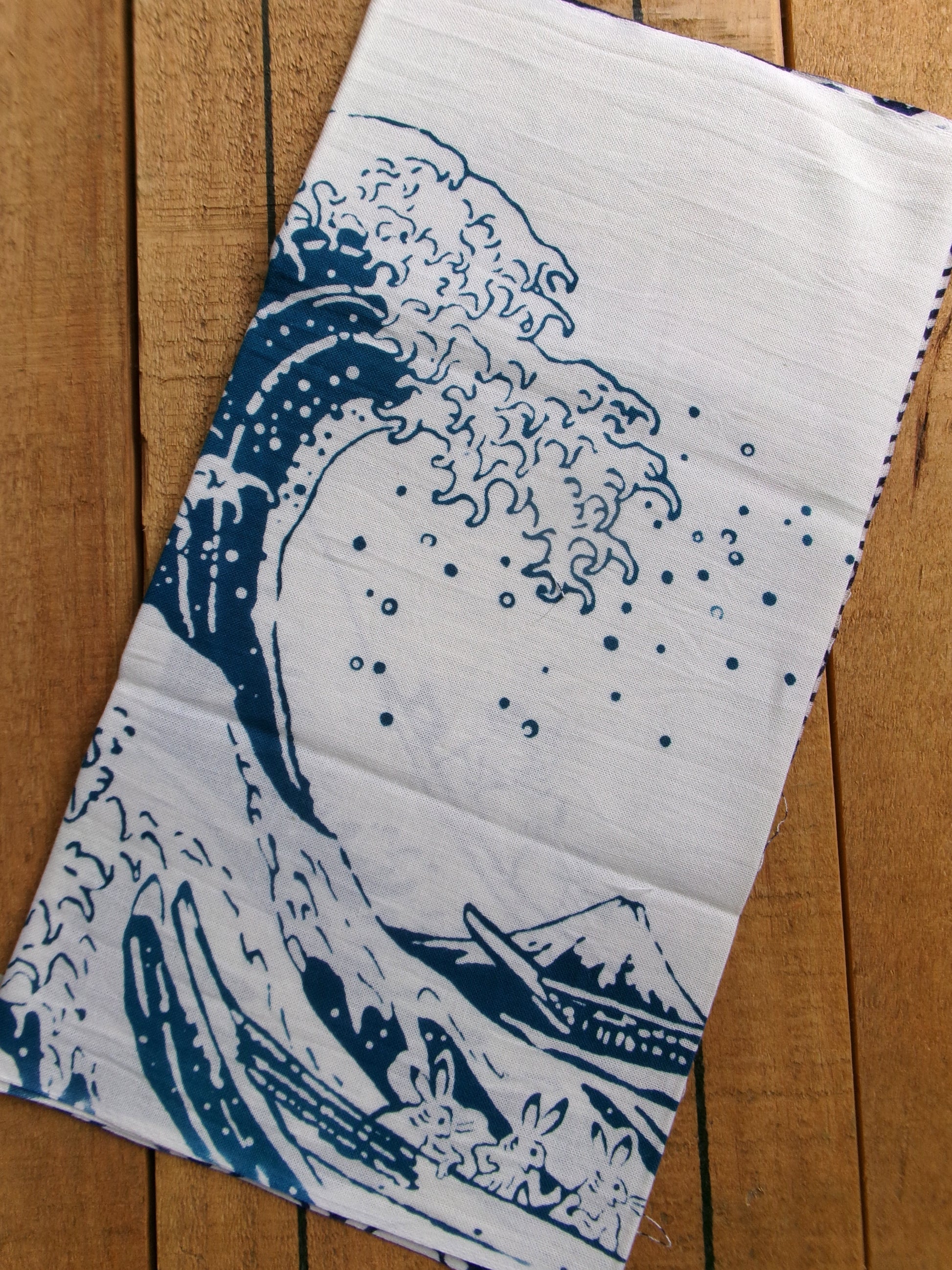 Traditional tenugui cloth featuring Chōjū-giga and The Great Wave off Kanagawa designs by Kamawanu, with detailed Japanese artwork.