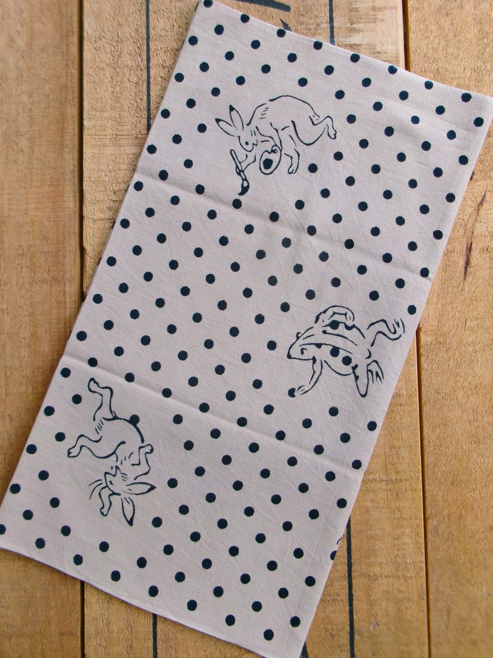 Beige tenugui featuring traditional Mameshibori pattern with bird and beast motifs, by Kamawanu, showcasing intricate Japanese textile design.