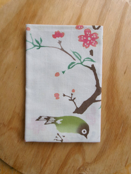 Cotton tenugui towel featuring cherry blossoms and a Japanese white-eye bird in traditional Japanese design by Kamawanu.