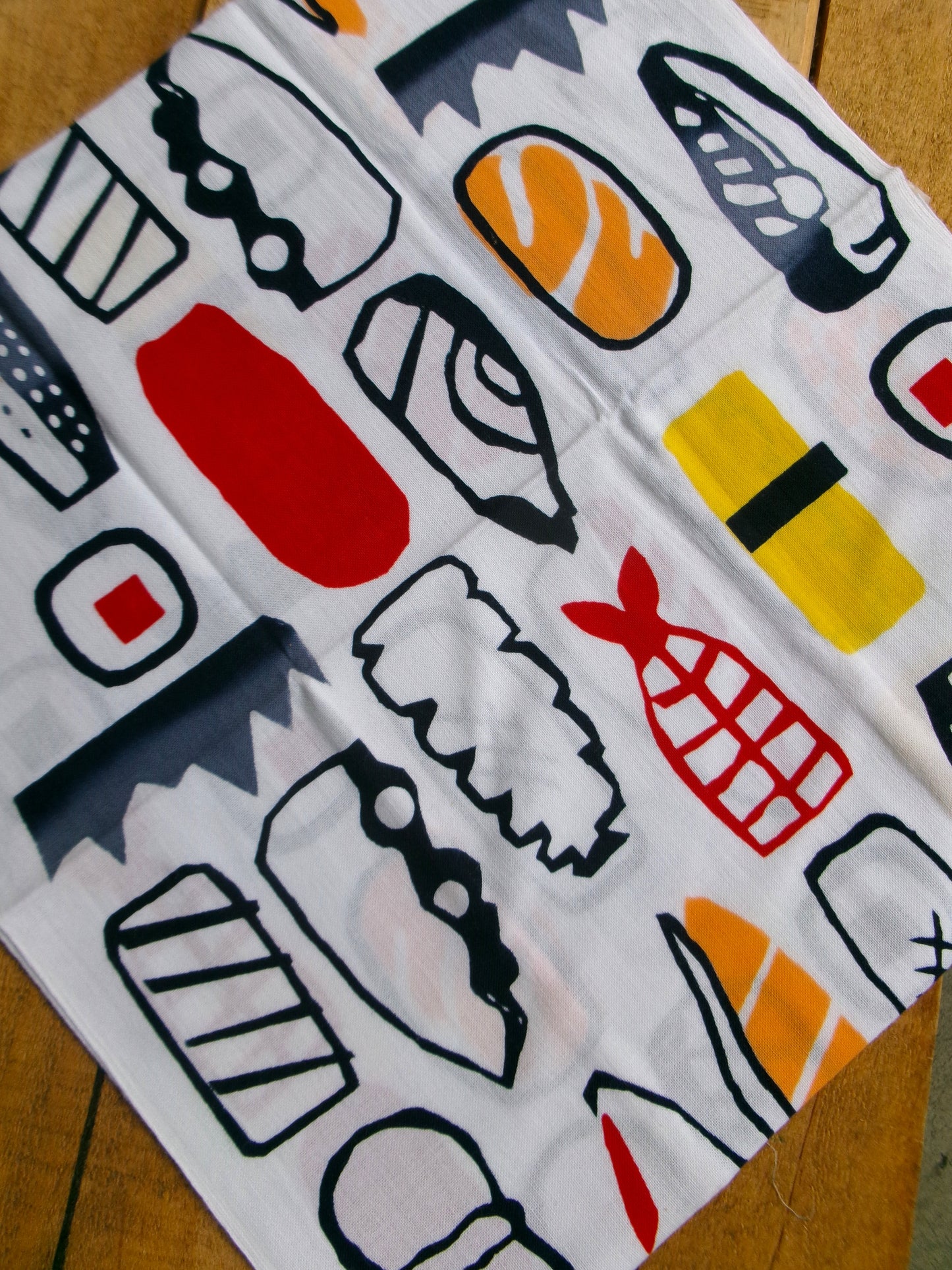 Traditional Japanese tenugui cloth featuring sushi-themed design by Kamaranu, displayed flat with vibrant sushi illustrations.